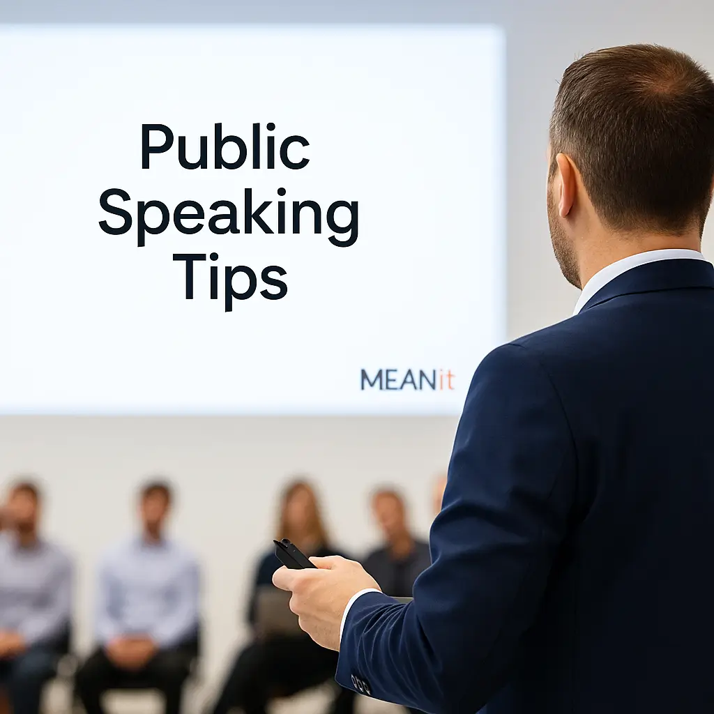 Over the shoulder view of a presenter holding a clicker with a blurred audience and a slide that reads Public Speaking Tips with MEANit branding